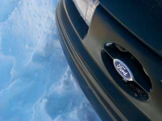 1994 Ford Taurus - Close-up of a Ford emblem on the front of a dark-colored vehicle.