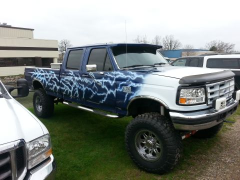 1995 Ford Bronco - This lifted Ford F-350 truck features custom lightning bolt paintwork on its side and hood.