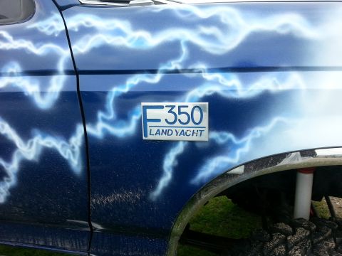1995 Ford Bronco - Custom blue truck with lightning graphics and an F350 LAND YACHT badge.