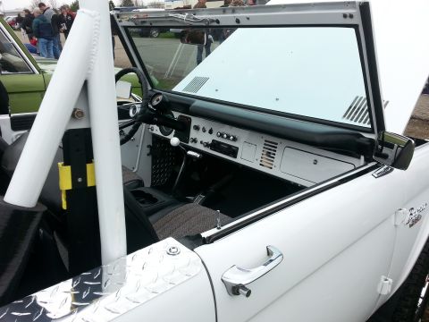 1995 Ford Bronco - The interior of a white Ford Bronco is visible, alongside another Bronco in green.