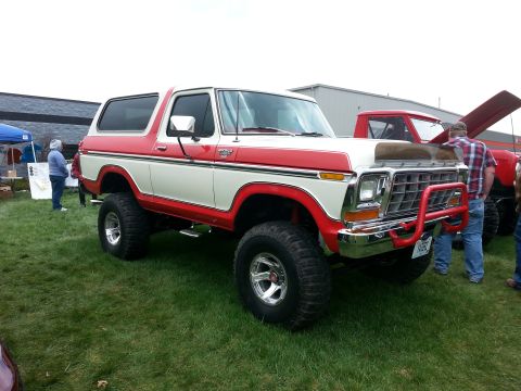 1995 Ford Bronco - This lifted Ford Bronco features a two-tone red and white paint scheme and a prominent red bull bar.