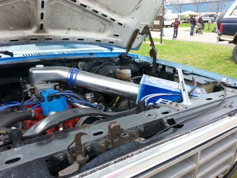 1995 Ford Bronco - The engine bay of a vehicle is open, showing the engine and an aftermarket intake system.