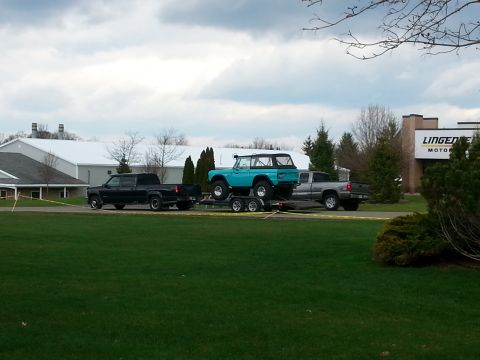 1995 Ford Bronco - A blue Ford Bronco is transported on a trailer, accompanied by two pickup trucks.