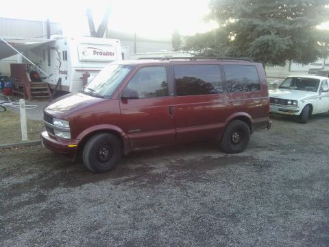 2000 Chevrolet Astro - This 2000 Chevrolet Astro van is parked next to a white car and a trailer.