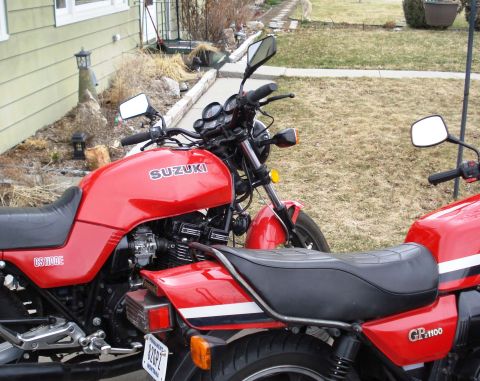 2008 Ford Crown Victoria - Two red Suzuki motorcycles are parked side-by-side in front of a house, with one clearly labeled GS1100E and the other GP1100.