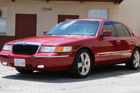 2002 Mercury Grand Marquis - A red 2002 Mercury Grand Marquis sedan is shown from the front 3/4 view. The license plate reads 'EVIL MGM'.