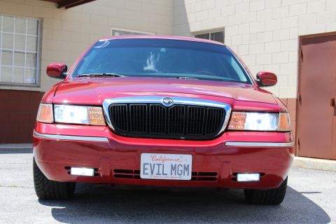 2002 Mercury Grand Marquis - The front of a red Mercury Grand Marquis is shown, its distinctive grille and a personalized license plate.