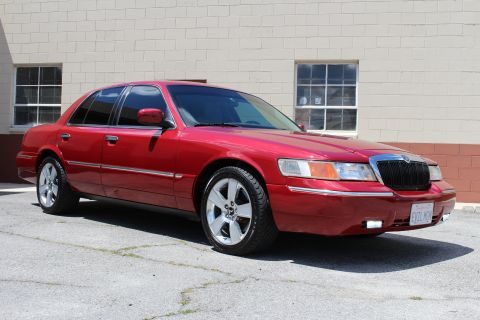 2002 Mercury Grand Marquis - Red 2002 Mercury Grand Marquis parked in front of a brick building.