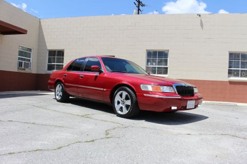 2002 Mercury Grand Marquis - A red 2002 Mercury Grand Marquis is shown from a three-quarter front view, parked outside a building.