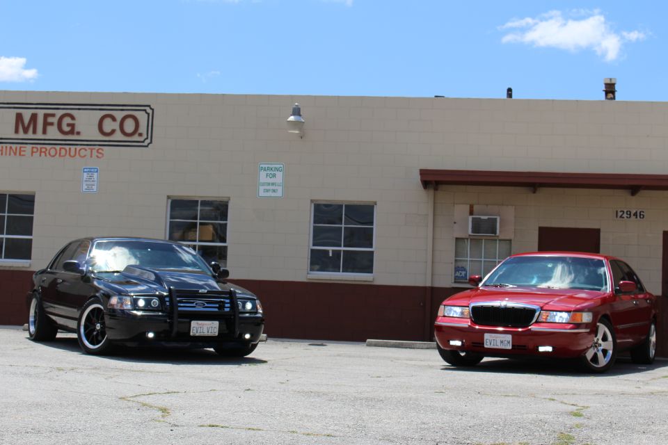 Red 2002 Mercury Grand Marquis parked next to a black sedan