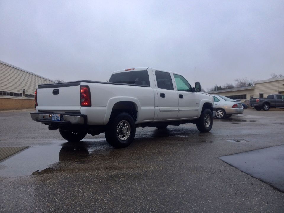 White 2006 Chevrolet Silverado 2500 crew cab pickup truck parked on wet asphalt