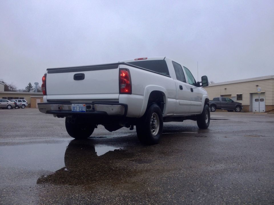 White 2006 Chevrolet Silverado 2500 pickup truck, rear 3/4 view, wet asphalt, overcast sky