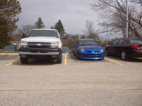 2006 Chevrolet Silverado 2500 - A white Chevrolet Silverado pickup truck is parked in a lot next to a blue Dodge Neon SRT-4 and a dark sedan.