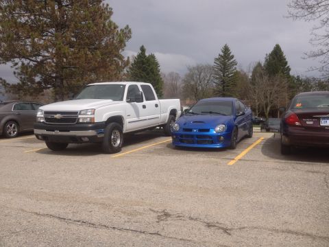 2006 Chevrolet Silverado 2500 - A white Chevrolet Silverado 2500 pickup truck is parked next to a blue Dodge Neon.