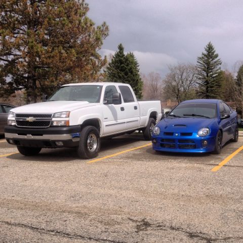 2006 Chevrolet Silverado 2500 - A white 2006 Chevrolet Silverado 2500 pickup truck is parked next to a blue Dodge Neon in a parking lot.