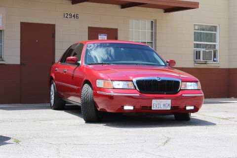 2002 Mercury Grand Marquis - Front view of a red 2002 Mercury Grand Marquis parked in front of a building.