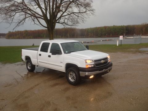 2006 Chevrolet Silverado 2500 - A white 2006 Chevrolet Silverado 2500 pickup truck is parked near a body of water on a cloudy day.