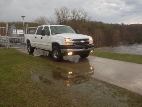 2006 Chevrolet Silverado 2500 - White 2006 Chevrolet Silverado 2500 pickup truck parked on wet pavement near a body of water.