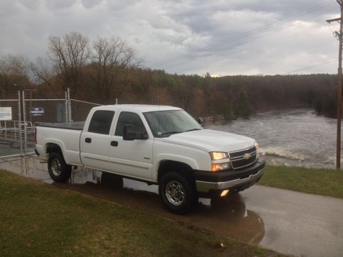 2006 Chevrolet Silverado 2500 - This white 2006 Chevrolet Silverado 2500 is seen from a three-quarter front view, parked near a flowing river under a cloudy sky.