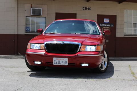2002 Mercury Grand Marquis - A red 2002 Mercury Grand Marquis is parked in front of a building with the number 12946 visible.