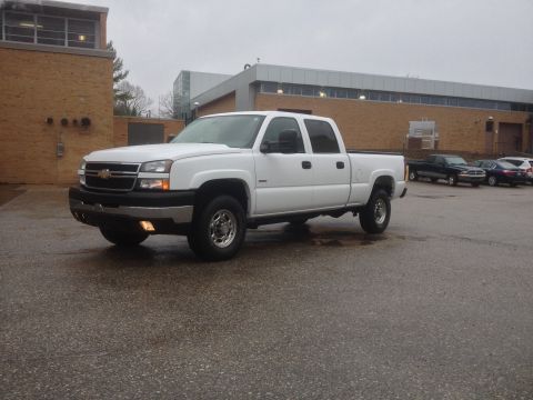 2006 Chevrolet Silverado 2500 - A white 2006 Chevrolet Silverado 2500 pickup truck is parked in a lot on an overcast day.