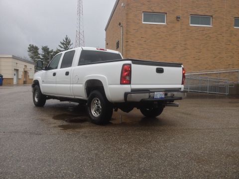 2006 Chevrolet Silverado 2500 - Rear view of a white 2006 Chevrolet Silverado 2500 pickup truck parked outside a brick building.
