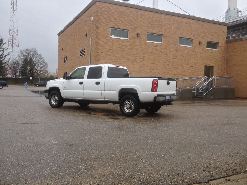 White 2006 Chevrolet Silverado 2500 crew cab pickup truck parked outside a brick building