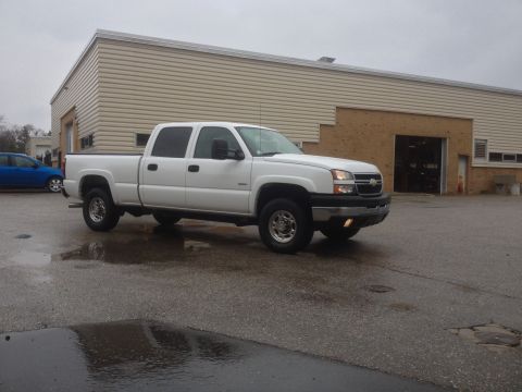 2006 Chevrolet Silverado 2500 - A white Chevrolet Silverado pickup truck is parked in front of a commercial building on a cloudy day.