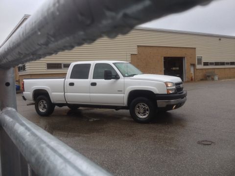 2006 Chevrolet Silverado 2500 - A white 2006 Chevrolet Silverado 2500 pickup truck is parked outside a building on a cloudy day.