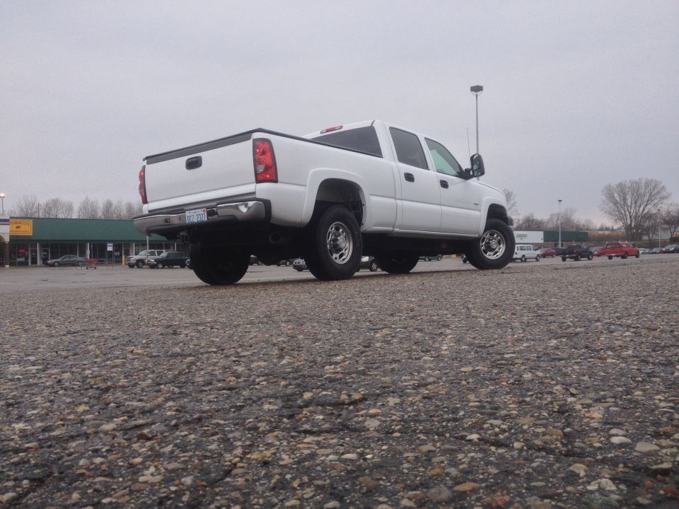 White pickup truck, rear 3/4 view, with chrome wheels and dual rear tires