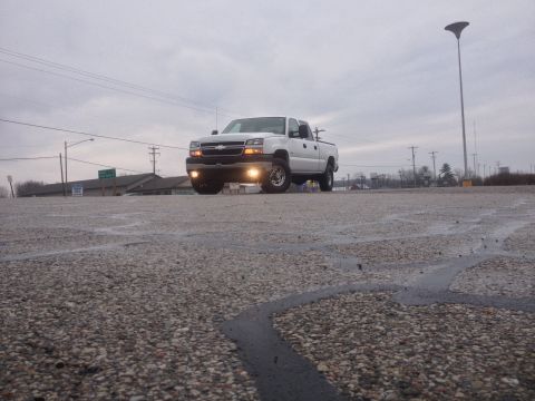 2006 Chevrolet Silverado 2500 - A white 2006 Chevrolet Silverado 2500 pickup truck is seen from a low angle on a cloudy day.