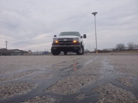 2006 Chevrolet Silverado 2500 - A white 2006 Chevrolet Silverado 2500 pickup truck is seen from a low angle on a cloudy day.