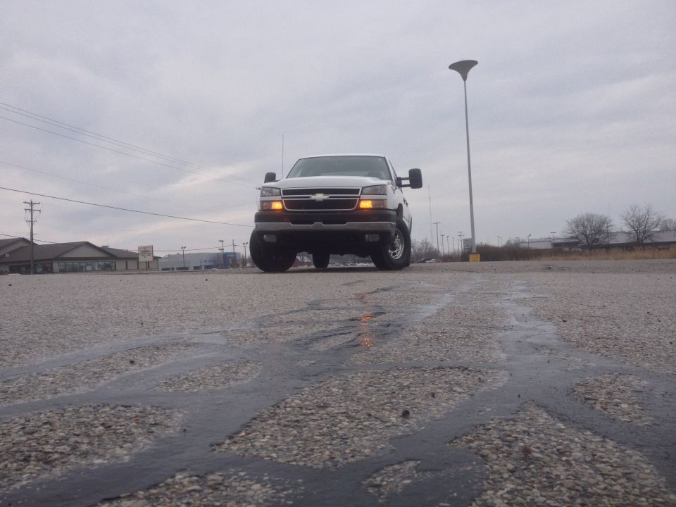 Front view of a white 2006 Chevrolet Silverado 2500 pickup truck parked on a wet asphalt lot