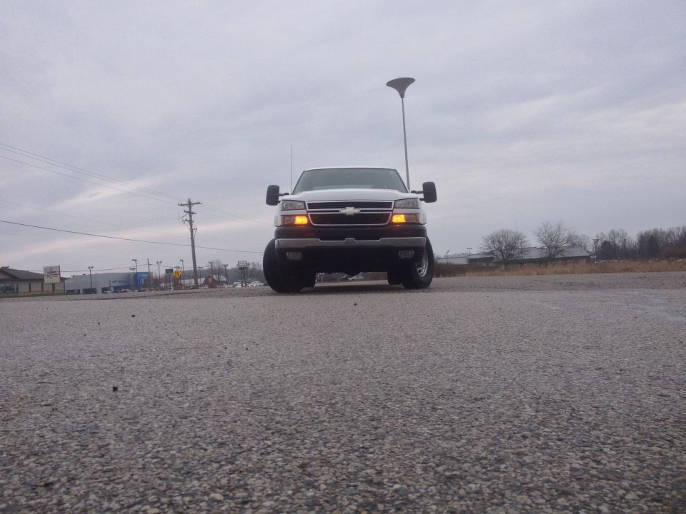 Silver Chevrolet Silverado 2500 front view, overcast sky, asphalt foreground