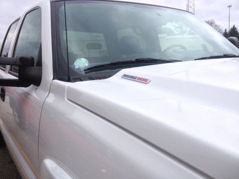 2006 Chevrolet Silverado 2500 - Close-up of a white pickup truck's hood and windshield, showing a Duramax Diesel badge and a sticker on the glass.