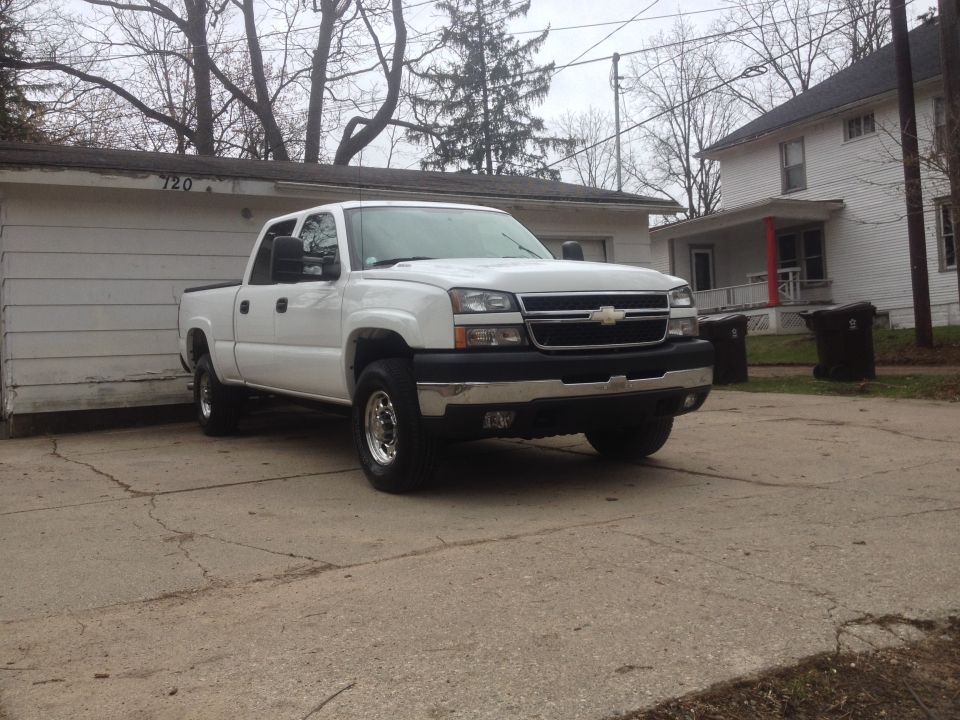 White Chevrolet Silverado pickup truck, front 3/4 view, parked in driveway