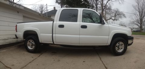 2006 Chevrolet Silverado 2500 - Side view of a white 2006 Chevrolet Silverado 2500 pickup truck parked in front of a garage.