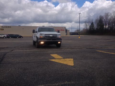 2006 Chevrolet Silverado 2500 - A white 2006 Chevrolet Silverado 2500 is parked in an empty lot under a cloudy sky.