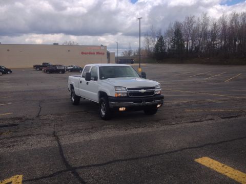 2006 Chevrolet Silverado 2500 - A white 2006 Chevrolet Silverado 2500 is parked in a lot with a building in the background.