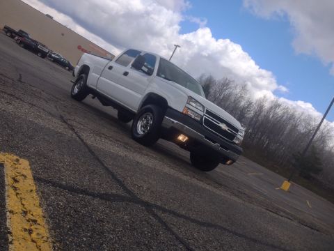 2006 Chevrolet Silverado 2500 - A white Chevrolet Silverado pickup truck is parked on an asphalt surface under a cloudy sky.