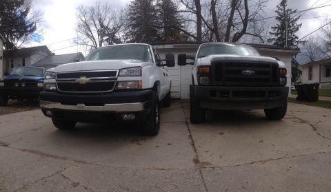2006 Chevrolet Silverado 2500 - Two pickup trucks, a Chevrolet and a Ford, are parked in a driveway.