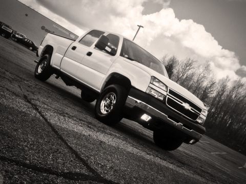 2006 Chevrolet Silverado 2500 - A white 2006 Chevrolet Silverado 2500 pickup truck is parked on a paved surface under a cloudy sky.