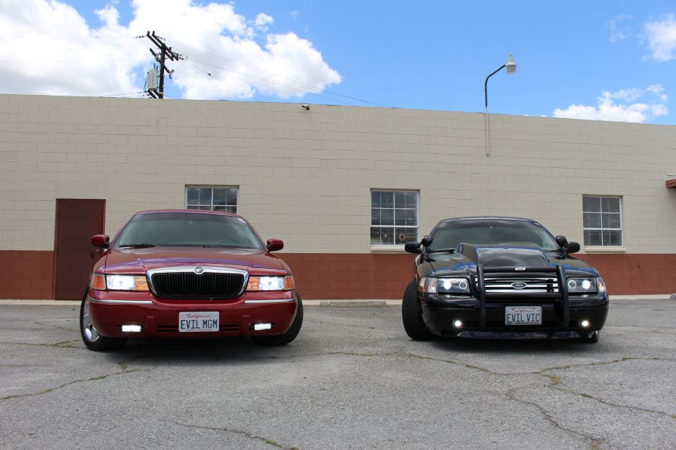 Red 2002 Mercury Grand Marquis and black modified car parked in front of a building