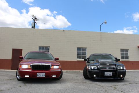 2002 Mercury Grand Marquis - Two sedans are parked side-by-side in front of a beige building under a cloudy sky.
