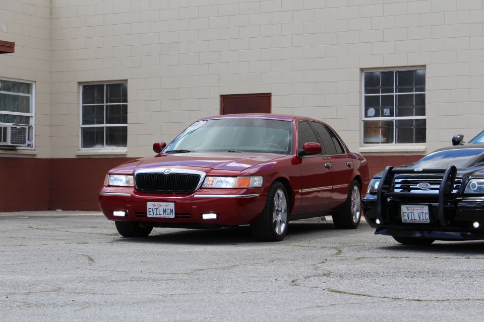 Red 2002 Mercury Grand Marquis parked next to a black police car