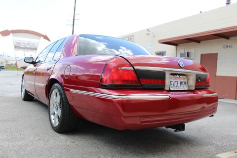 2002 Mercury Grand Marquis - The rear of a red sedan is shown, with a custom license plate and a trailer hitch.