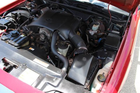 2002 Mercury Grand Marquis - The engine bay of a red vehicle is shown with the hood open, revealing the engine components and fluids.