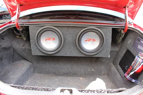 2002 Mercury Grand Marquis - The trunk of a red car is open, revealing a custom subwoofer box with two speakers and an amplifier installed.