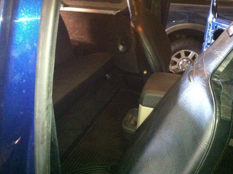 1982 Ford Bronco - View from inside a blue vehicle, looking towards the rear seats and a portion of another vehicle's wheel.
