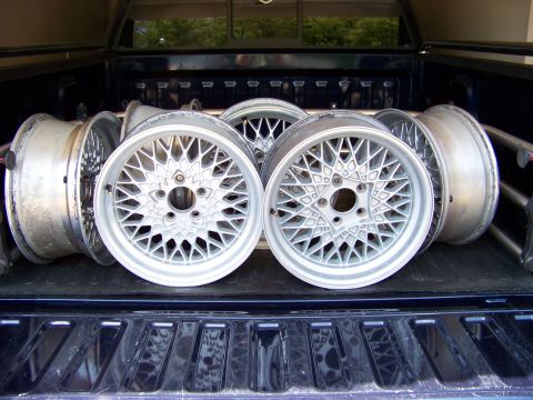 1999 Mercury Grand Marquis - A collection of silver mesh alloy wheels are arranged in the bed of a pickup truck.